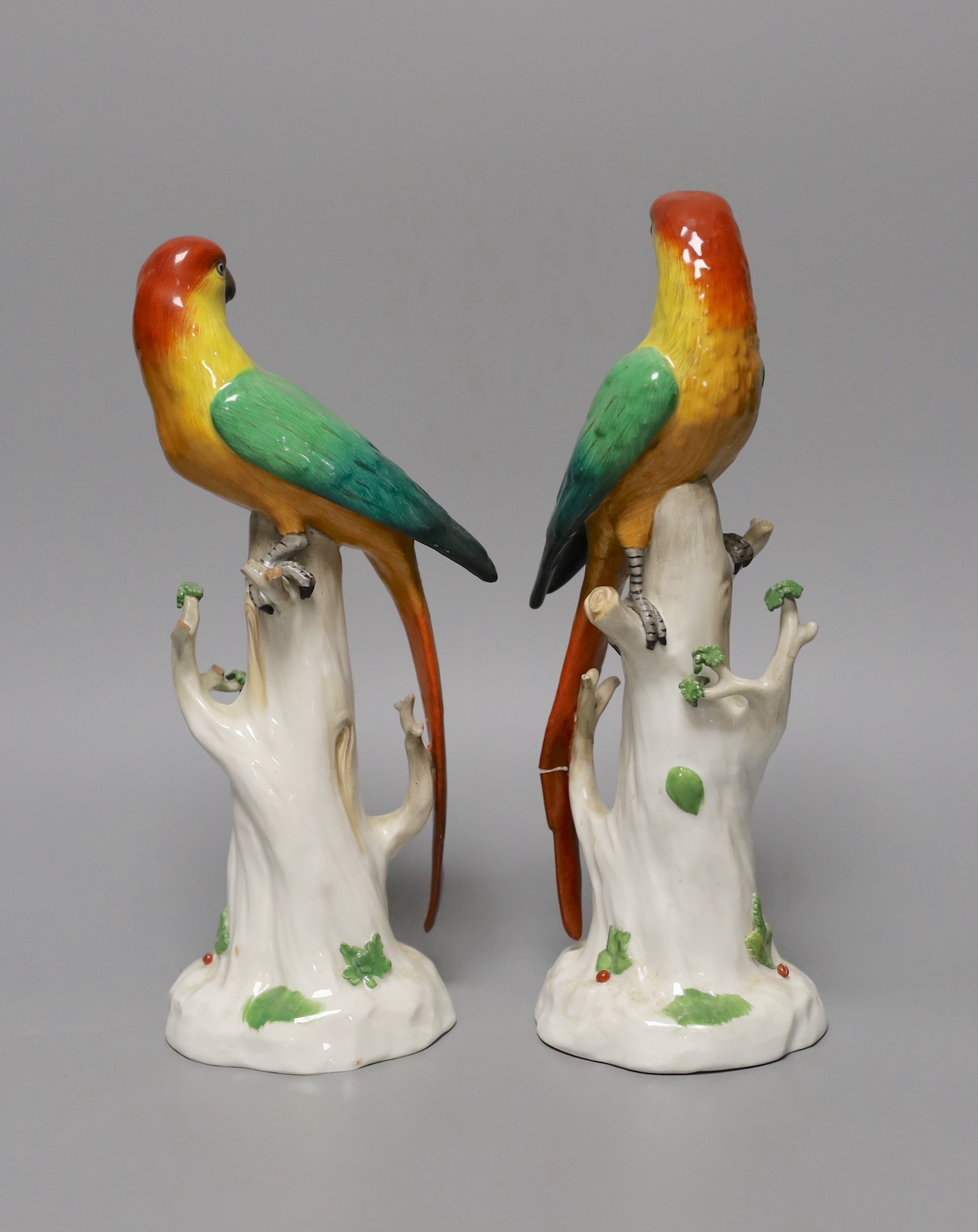 A pair of Continental porcelain perching parrots, 25cm tall